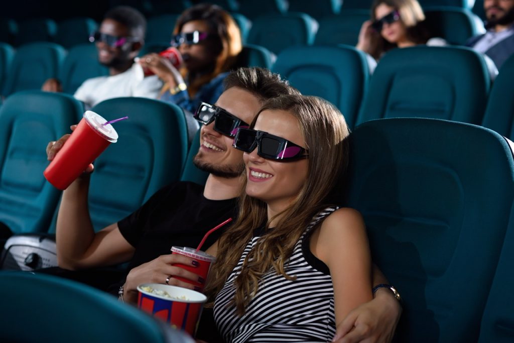 Movieholics. Gorgeous young woman smiling happily while cuddling with her handsome boyfriend during movies at the cinema