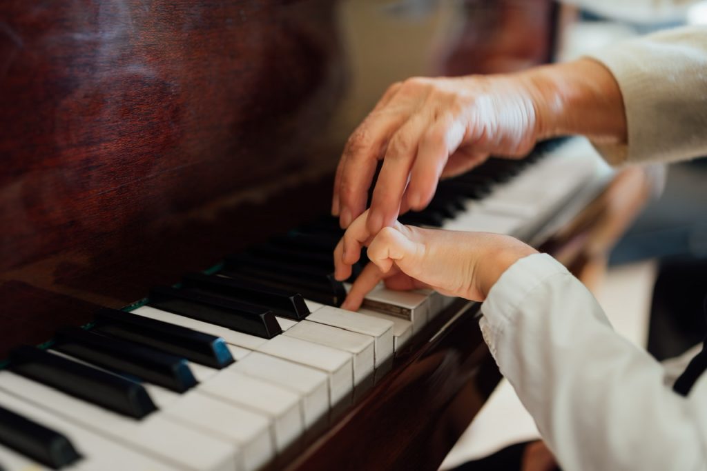 hand of an experienced pianist, music teacher helping young students By Artranq