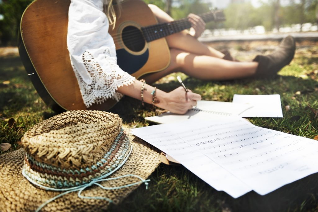 Closeup of woman guitarist sitting composing music in the park By Rawpixel