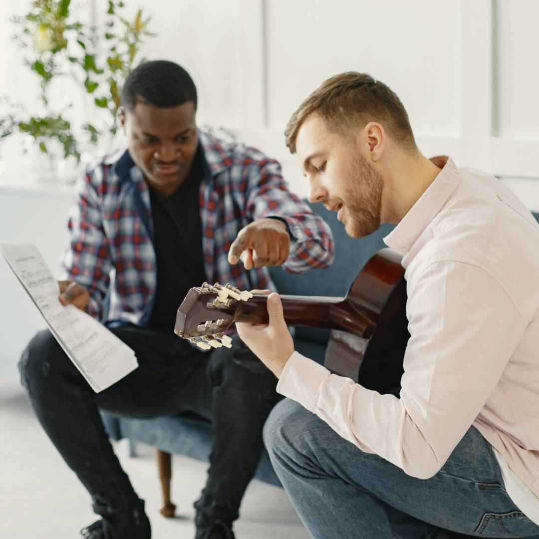 Teacher giving constructive criticism to guitar student.