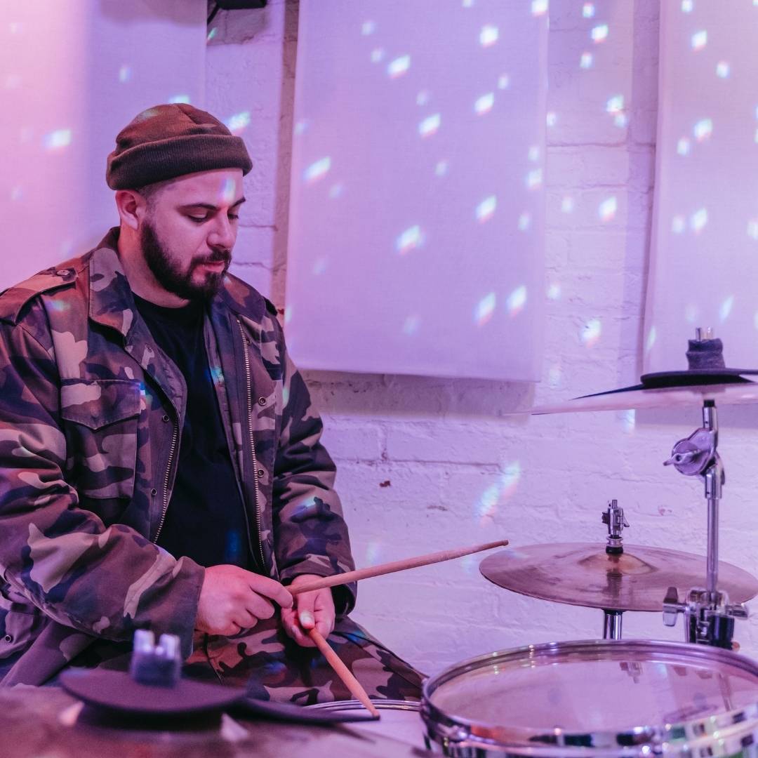 Man practicing drums in a rehearsal space.