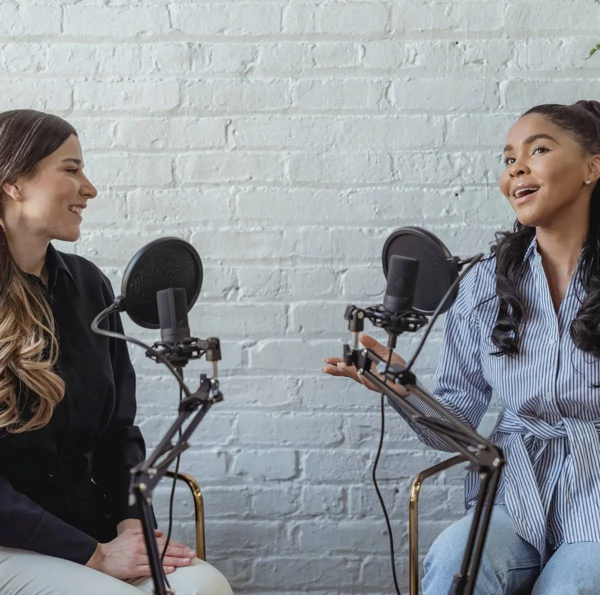 Two women sit in chairs with radio mics in front of them as they conduct an on air interview.