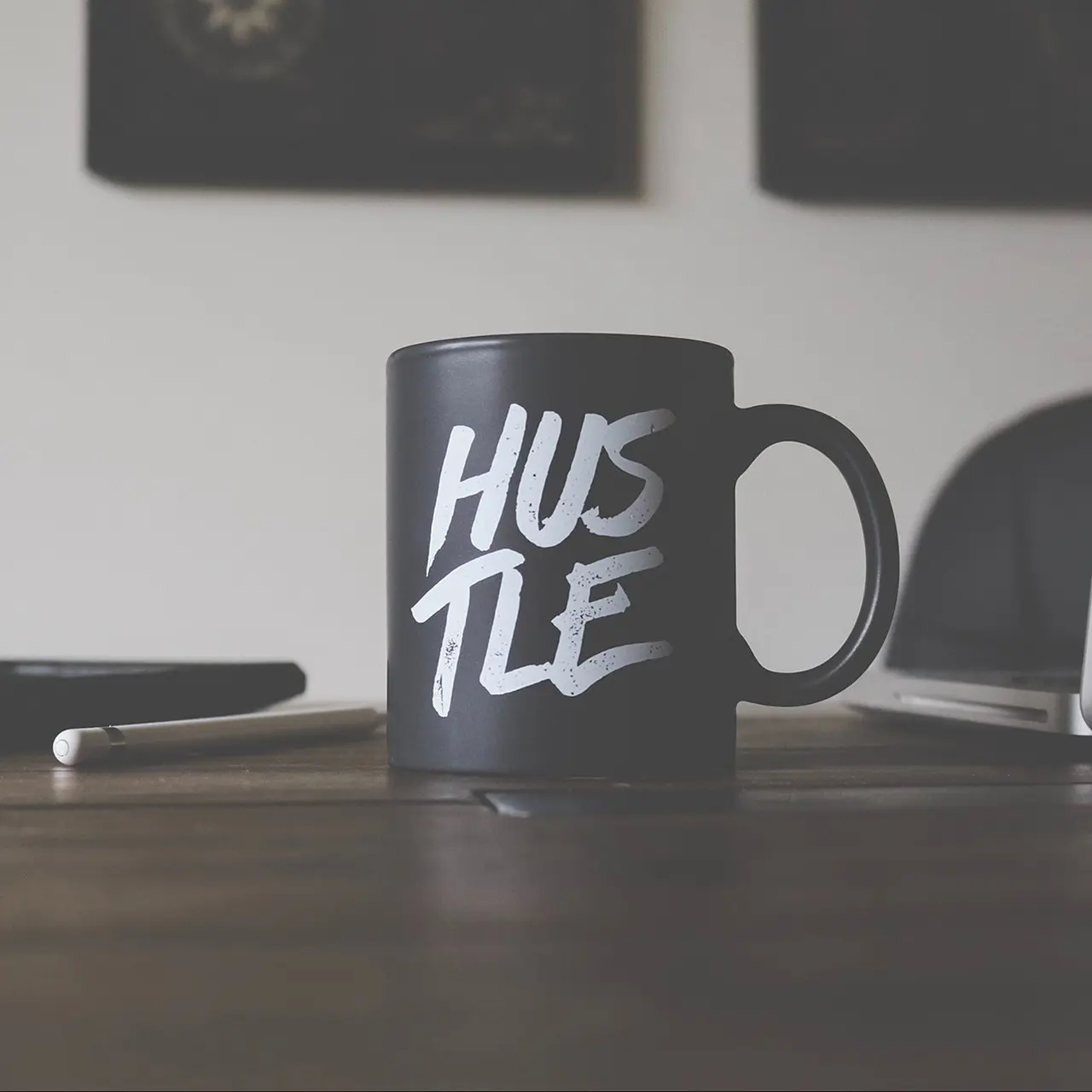 Black mug on desk that says hustle.