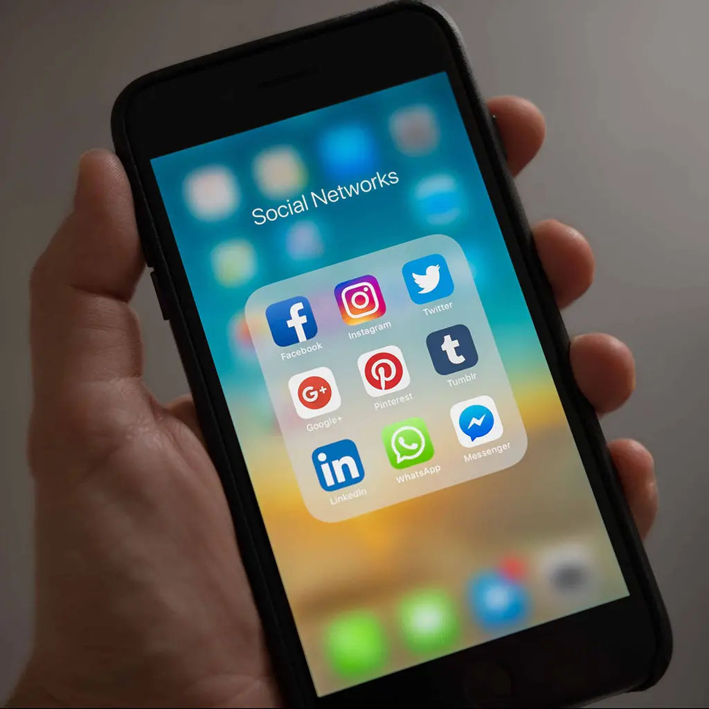 Social Media apps open on an iphone held up by a hand.