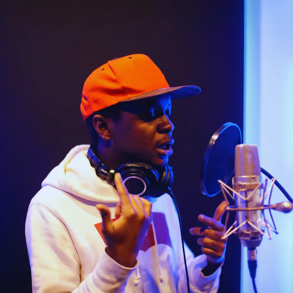 Digital marketing for musicians helps artists grow, represented by a rapper recording vocals in a professional studio.
