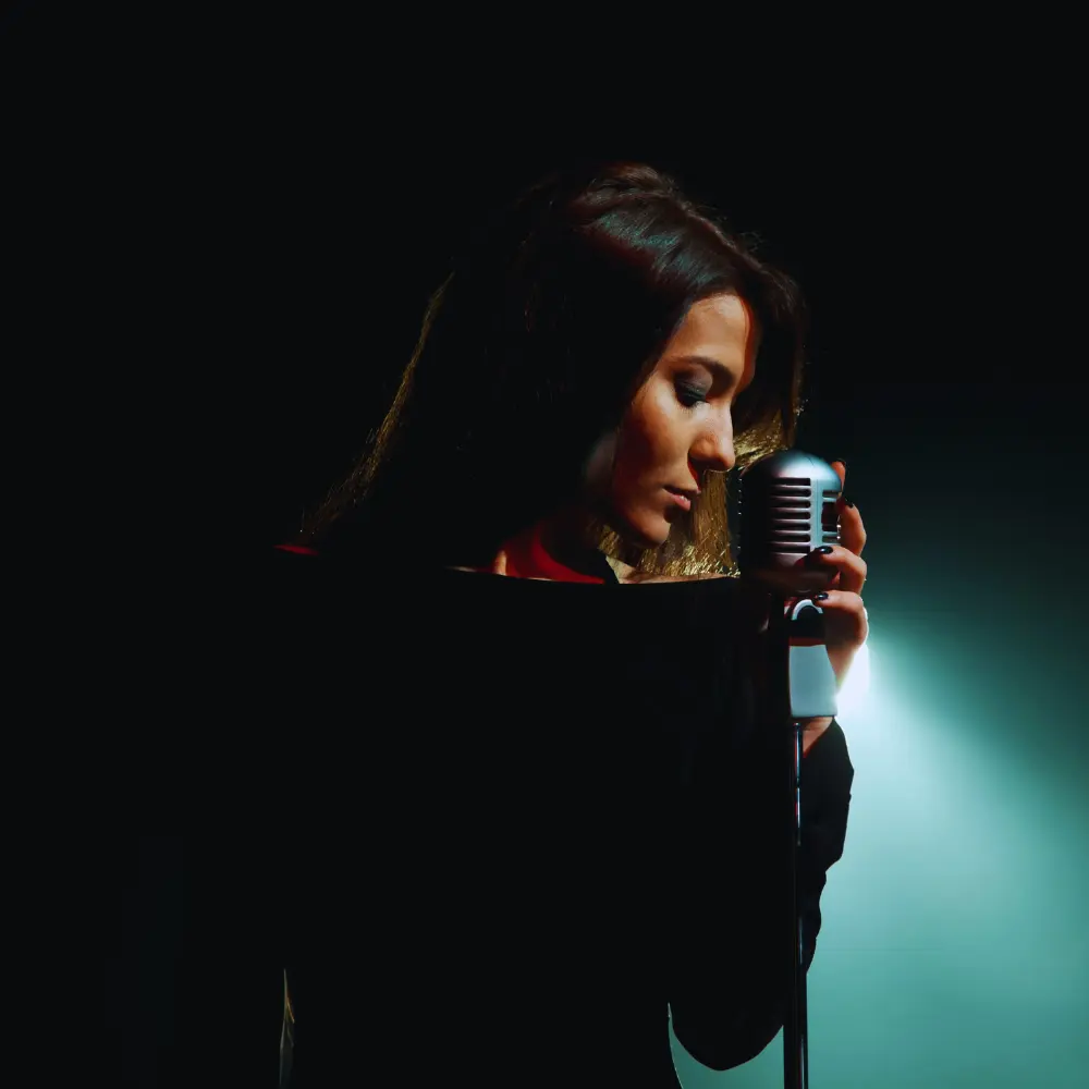 Getting music on streaming services is key for success, as shown by a singer performing emotionally with a vintage microphone.