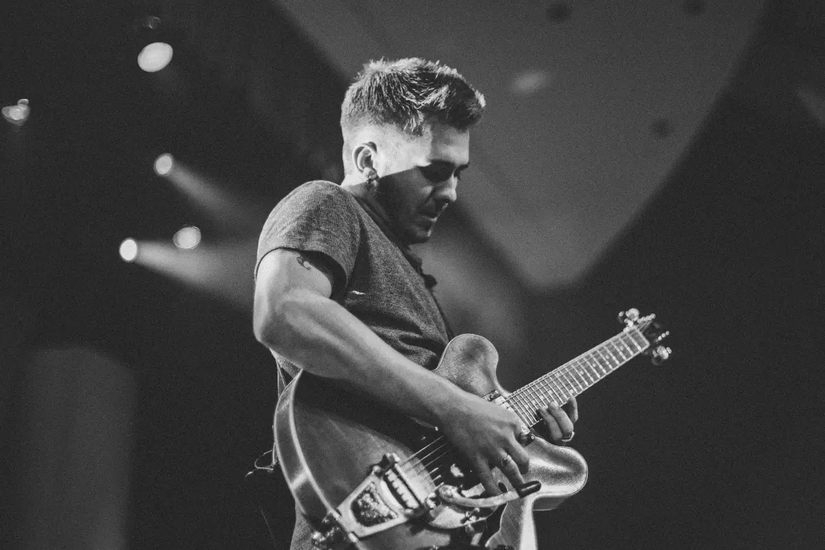 Social media for musicians is essential, just like this guitarist passionately performing on stage under dramatic lighting.
