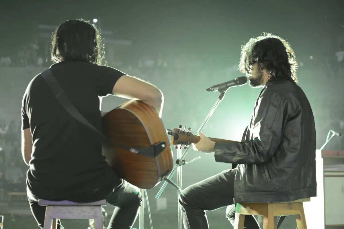 Music marketing with live acoustic performance by two musicians on stage under dramatic lighting