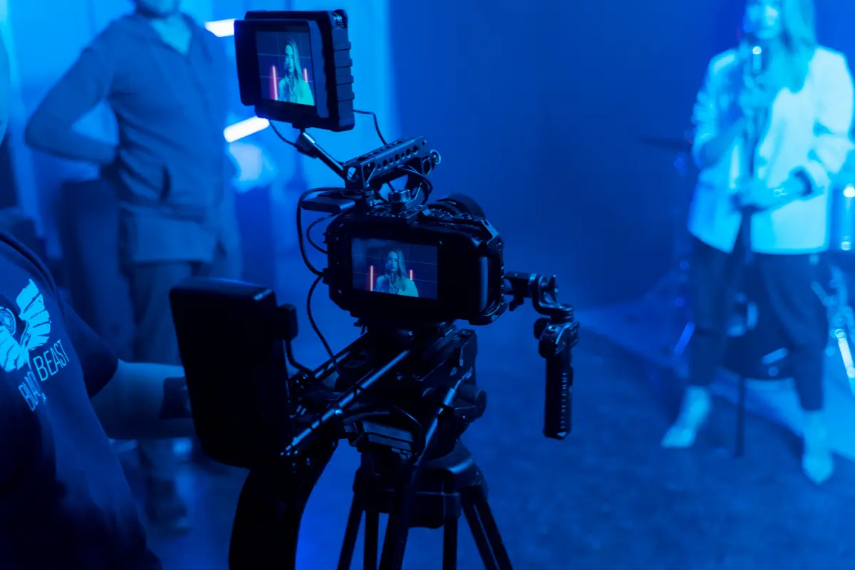 Music marketing with a professional video camera filming a female artist performing under dramatic blue stage lighting