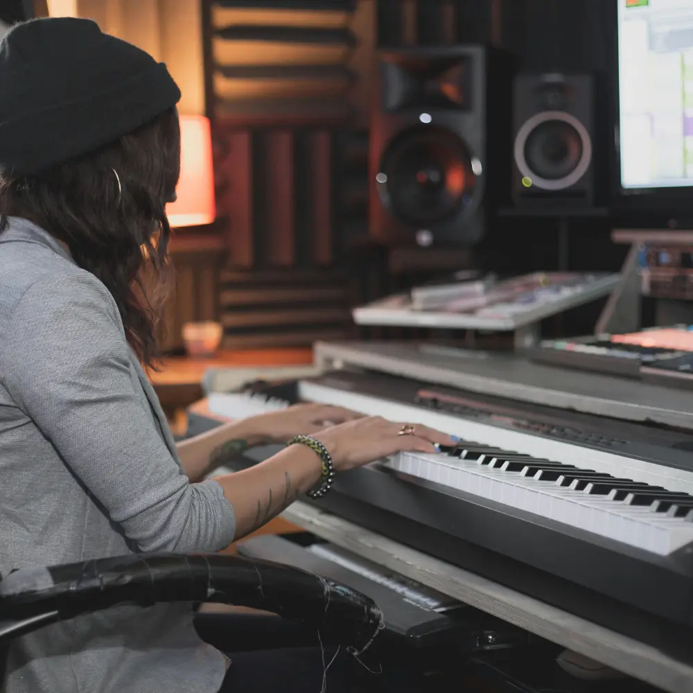 Platforms for music promotion with a woman playing keyboard in a soundproof recording studio surrounded by audio equipment.