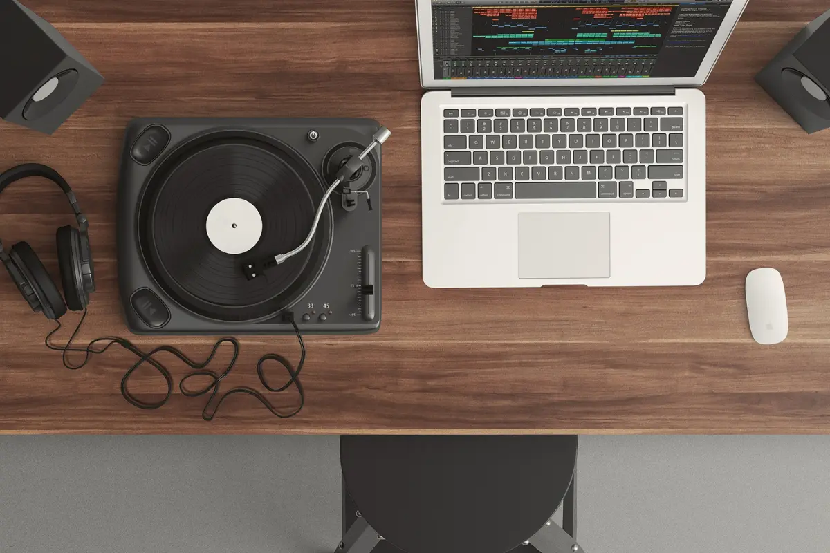 Social media for musicians with a turntable, headphones, and laptop displaying a music production interface on a wooden desk