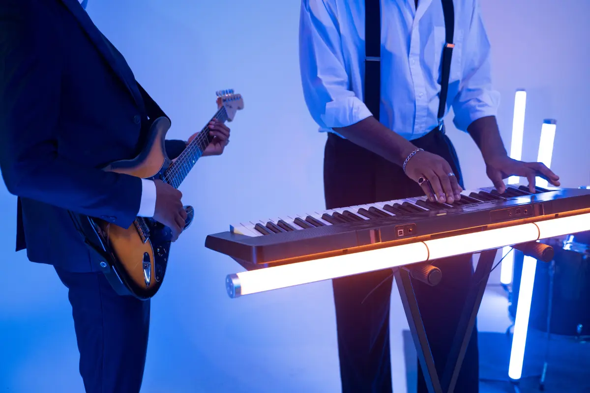 Social media promotion for musicians with two stylish men playing keyboard and electric guitar under blue stage lighting