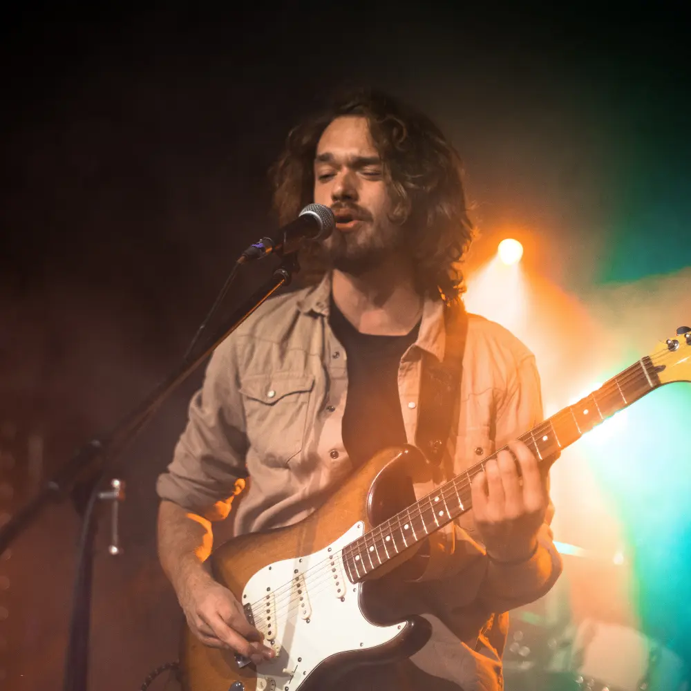 Music visual branding captured in a moody performance with a guitarist under colorful stage lighting