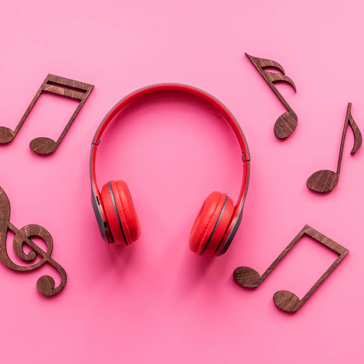Music portfolio inspiration concept with red headphones and wooden music notes on pink background.