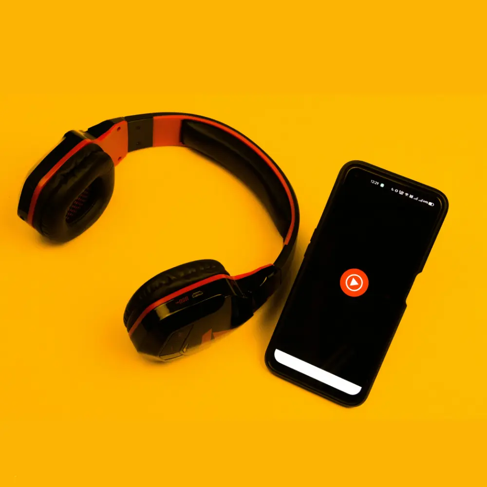 Music publishing concept with headphones and smartphone featuring a play button on vibrant yellow background.